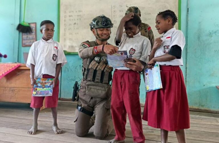 Teks Foto: Anggota Satgas Damai Cartenz saat membagikan buku kepada anak SD di Intan Jaya, Papua Tengah. (ist)